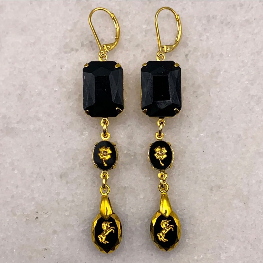 Gold and black earrings on a light gray background