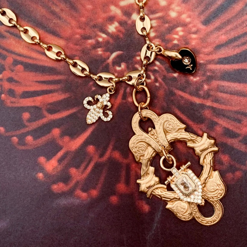 Gold necklace with intricate pendant on a textured red and black background