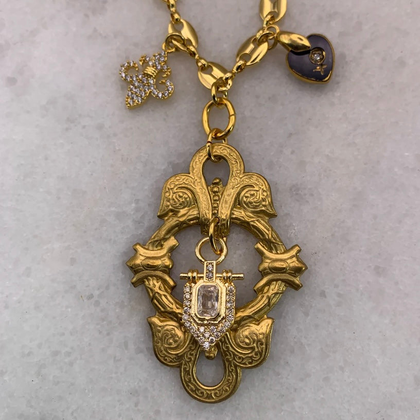 Gold necklace with an ornate pendant on a light gray background