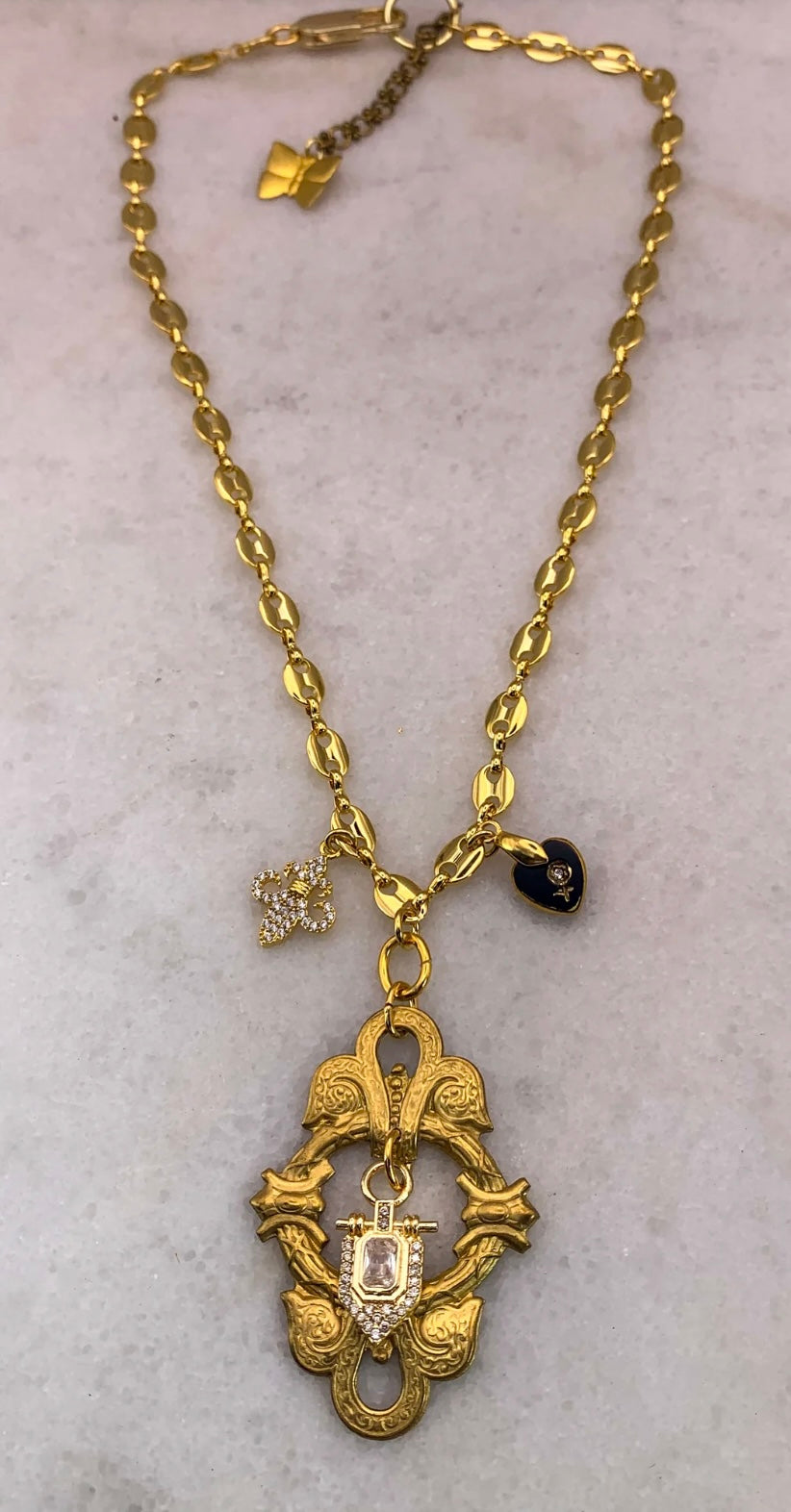 Gold necklace with various pendants on a light gray background