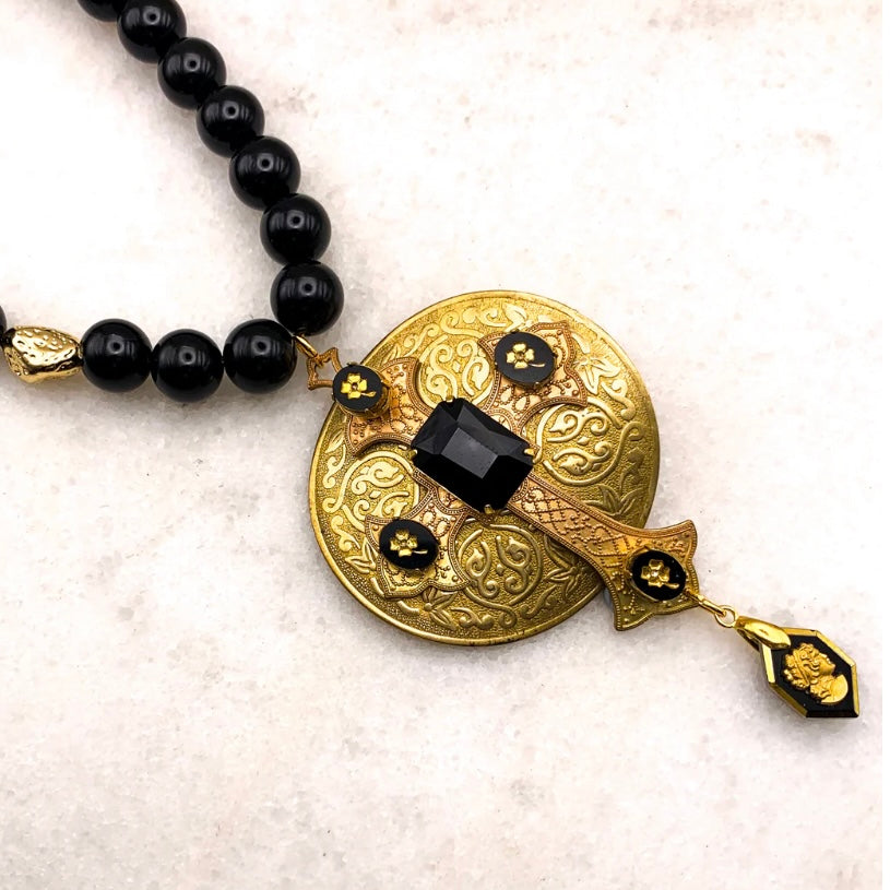 gold and black cross necklace on black onyx beads