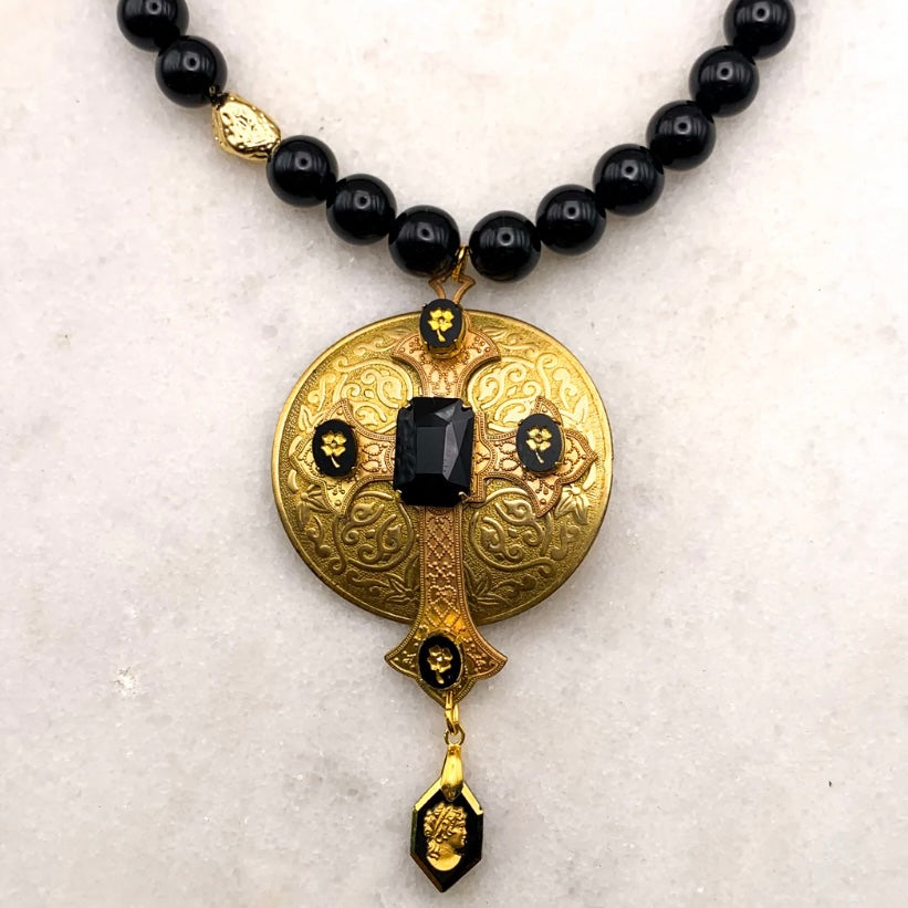 gold and black cross necklace on black onyx beads
