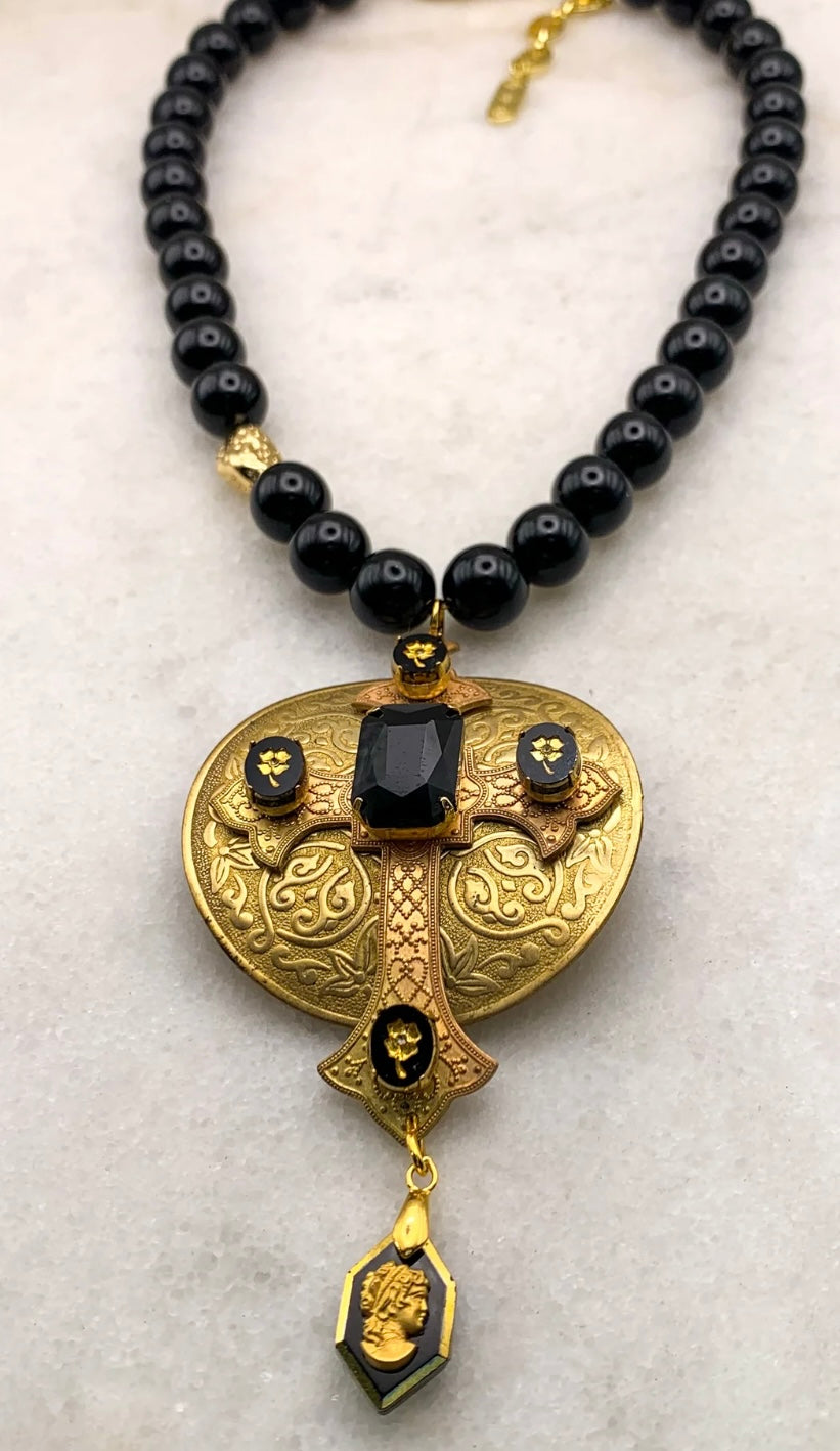 gold and black cross necklace on black onyx beads