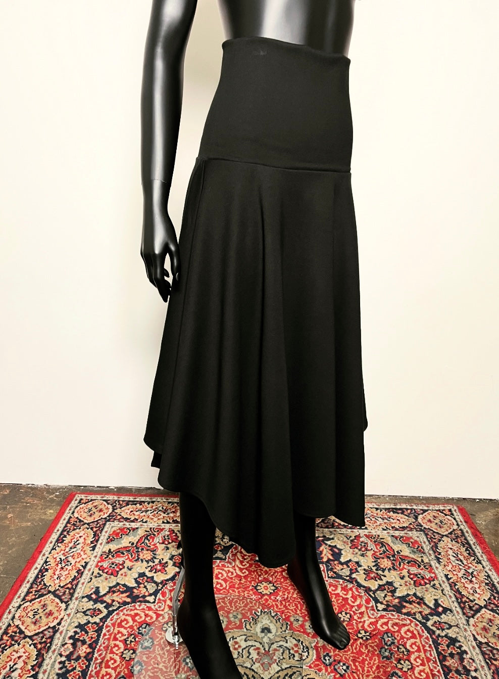 Black skirt on a mannequin against a plain background