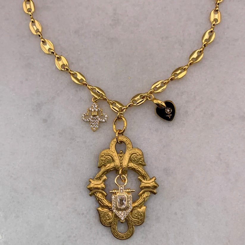 Gold necklace with decorative pendants on a gray background